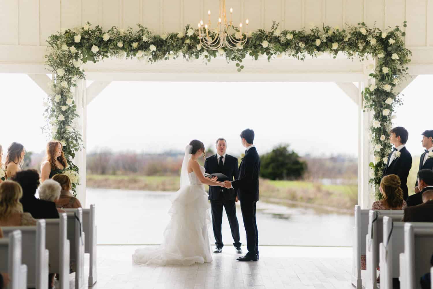 Elegant wedding ceremony with floral arch and bride and groom exchanging vows.