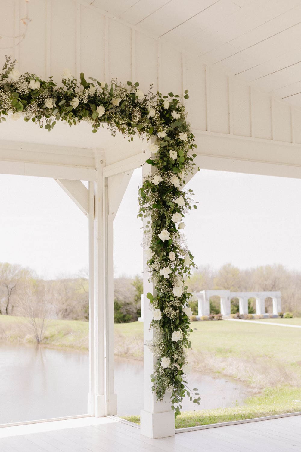 Beautiful floral arch with white roses and greenery for wedding decor.