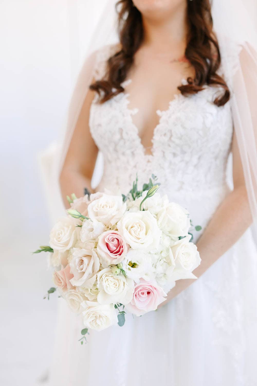 Bridal bouquet featuring white and blush roses, ideal for wedding floral arrangements.