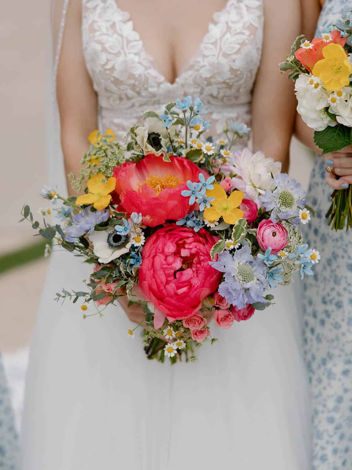 Bridal bouquet featuring colorful peonies, roses, and wildflowers for wedding floral arrangements.