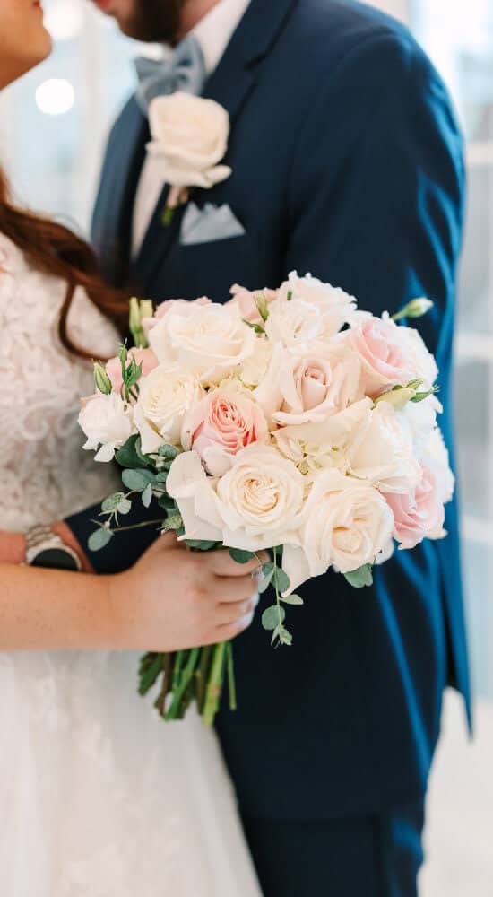 Beautiful wedding bouquet featuring white and blush roses with eucalyptus accents.