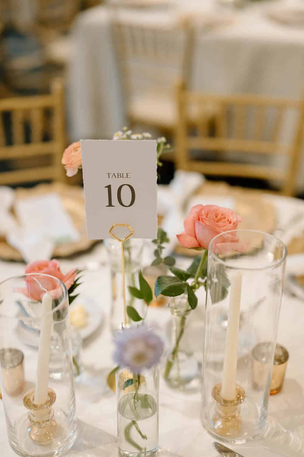 Elegant floral centerpiece with pink roses and white candles for wedding tables.