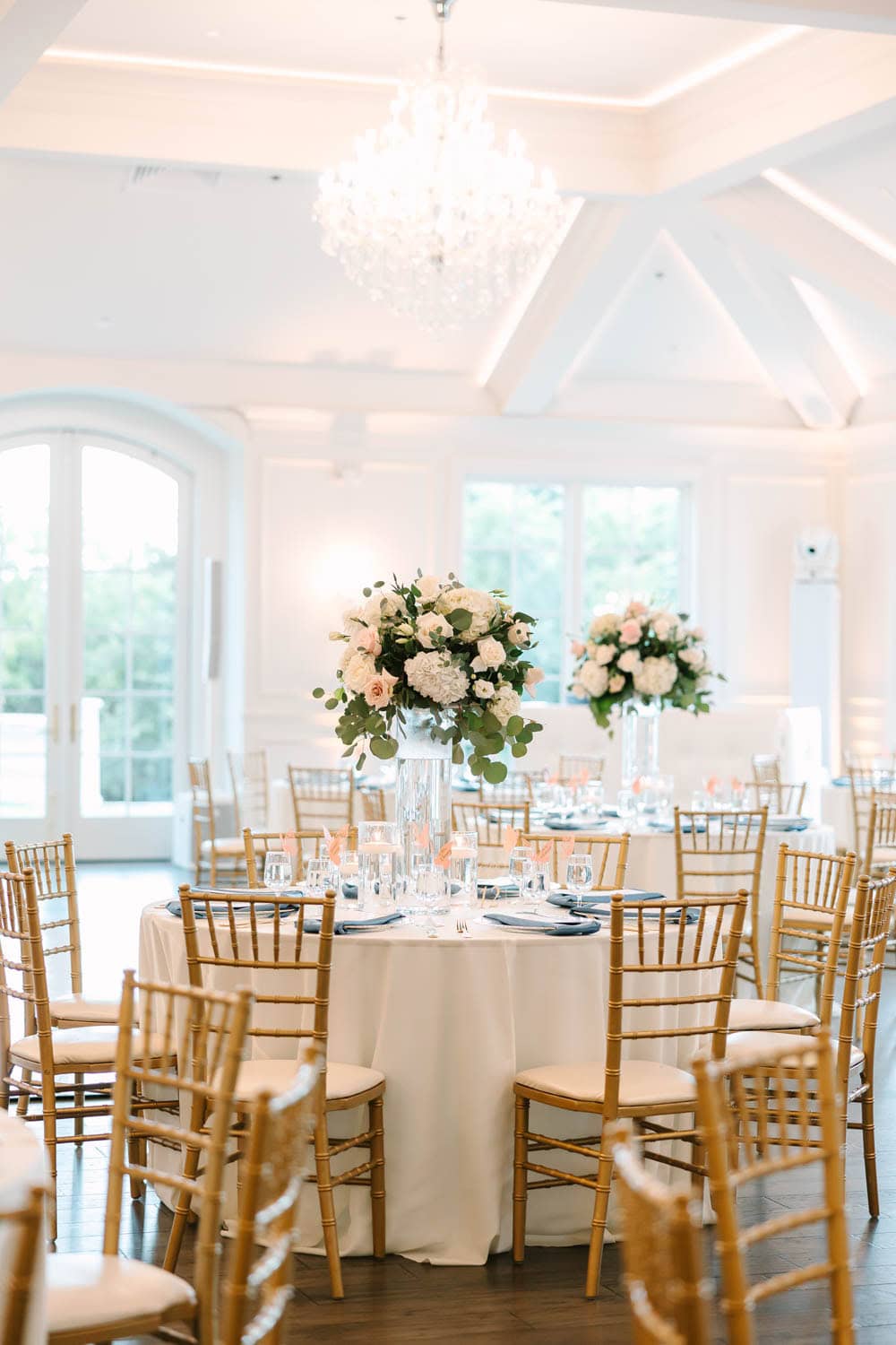Elegant floral centerpiece with white roses and greenery for wedding reception.