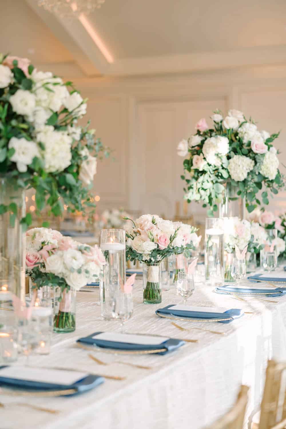 Beautiful floral arrangements featuring white and blush roses, hydrangeas, and greenery for wedding.