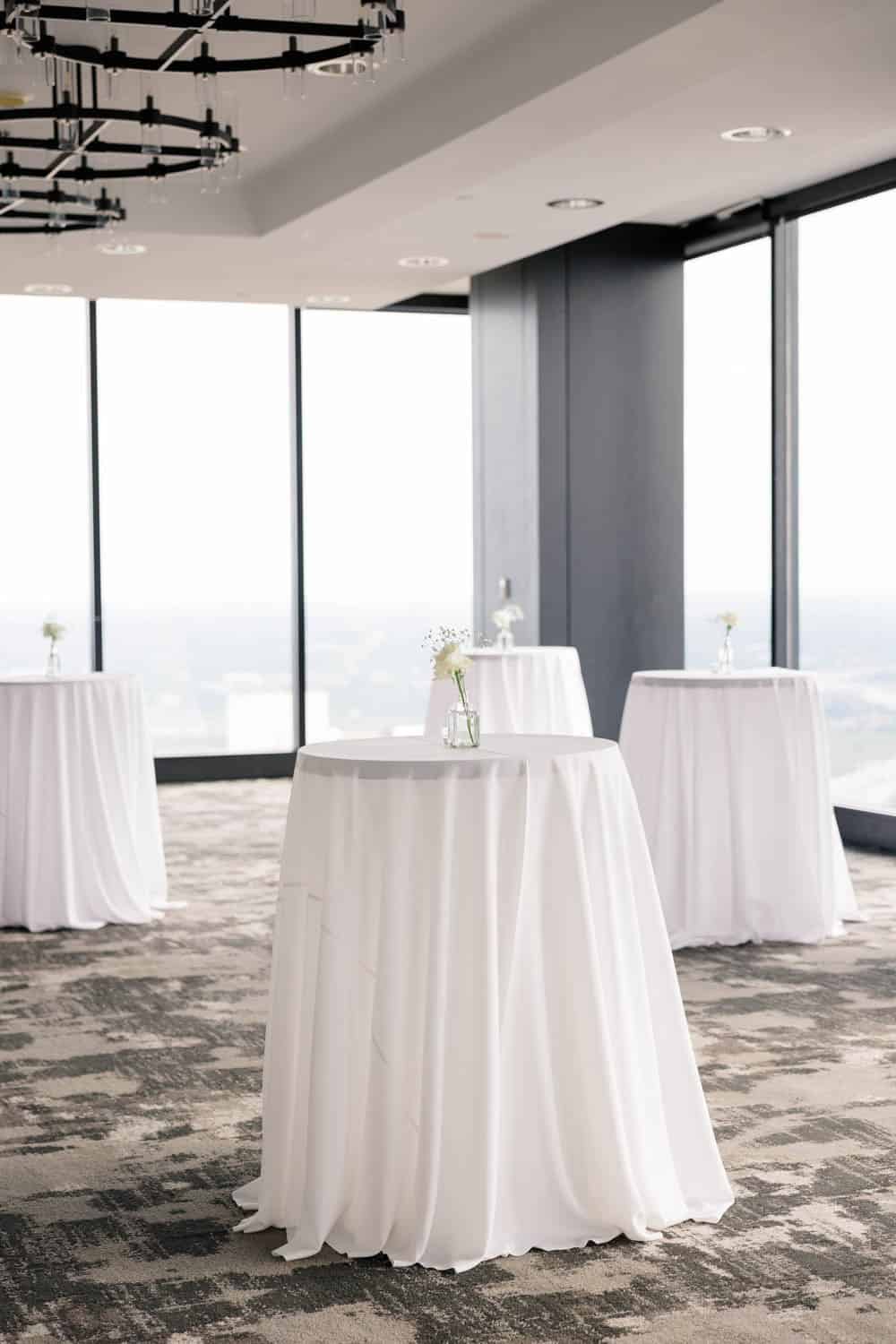 Beautiful floral arrangements on tall white tables in a modern event space.